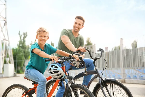 Feliz padre e hijo montando bicicletas al aire libre — Foto de Stock