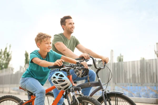 Feliz padre e hijo montando bicicletas al aire libre —  Fotos de Stock