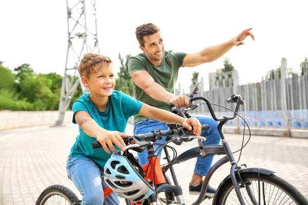 Lycklig far och son ridning cyklar utomhus — Stockfoto