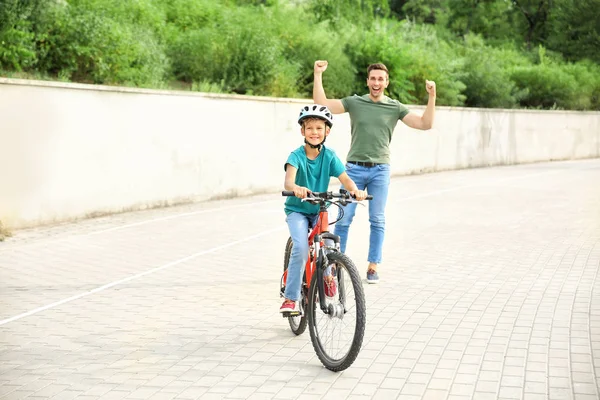 Padre orgulloso de su hijo que aprendió a andar en bicicleta al aire libre —  Fotos de Stock