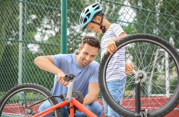 Father and his son repairing bicycle outdoors — Stock Photo, Image