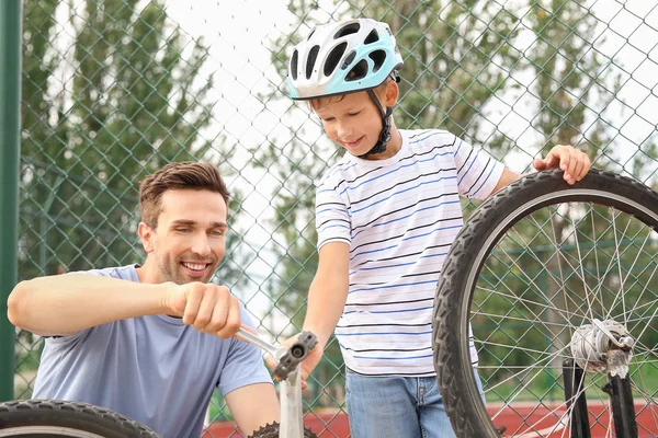 Father and his son repairing bicycle outdoors — Stock Photo, Image