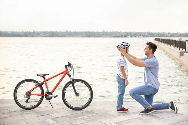 Père aidant son fils à mettre un casque avant de faire du vélo à l'extérieur — Photo