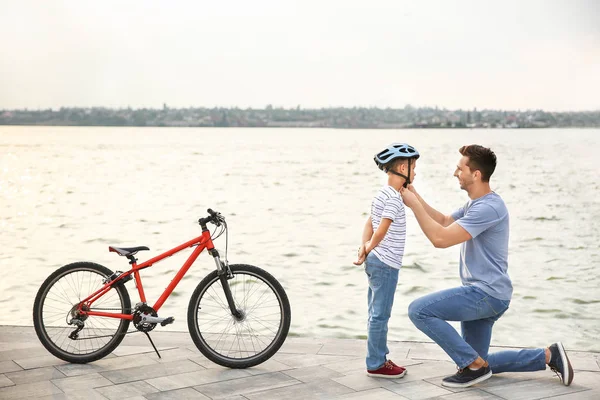 Père aidant son fils à mettre un casque avant de faire du vélo à l'extérieur — Photo