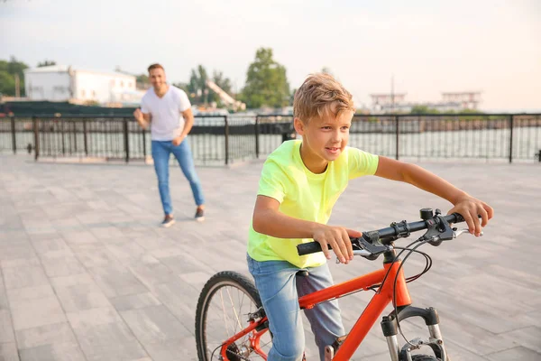 Pai orgulhoso de seu filho que aprendeu a andar de bicicleta ao ar livre — Fotografia de Stock