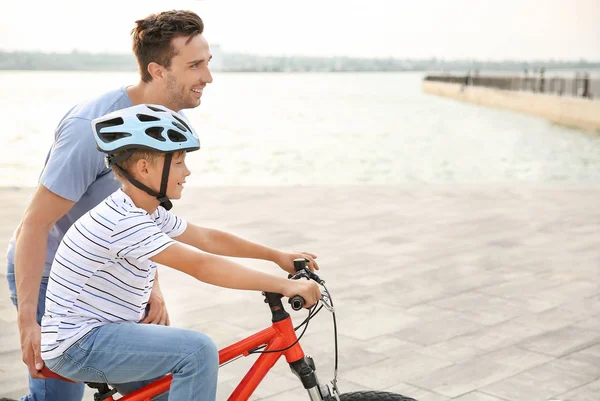 Padre enseñando a su hijo a andar en bicicleta al aire libre — Foto de Stock