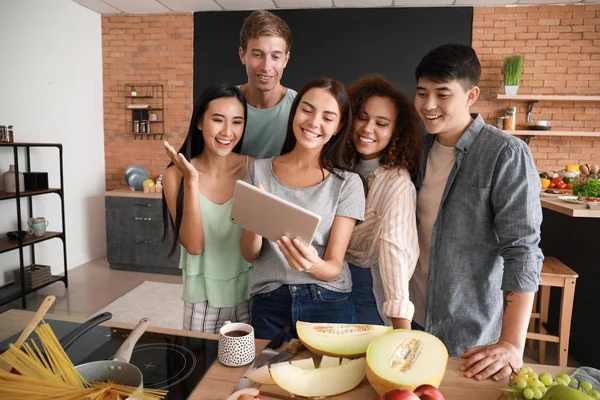 Amigos felizes com tablet computador procurando receita enquanto cozinham juntos na cozinha — Fotografia de Stock