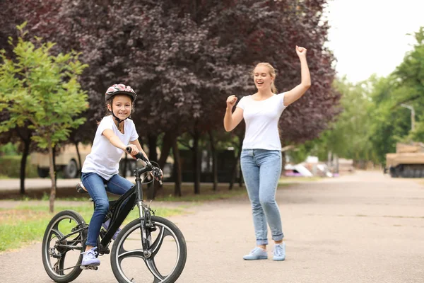 Mother proud of her daughter who learned to ride bicycle outdoors — Stock Photo, Image