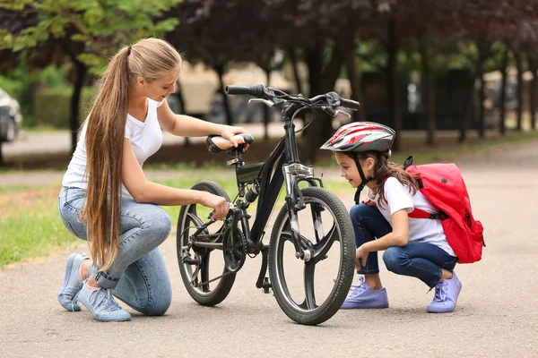 Mulher e sua filhinha com bicicleta ao ar livre — Fotografia de Stock