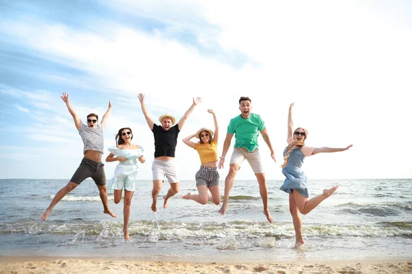 Felices amigos saltando en la playa del mar en el resort —  Fotos de Stock