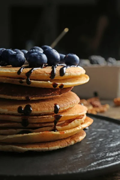 Piring dengan pancake lezat, blueberry dan coklat topping di atas meja — Stok Foto