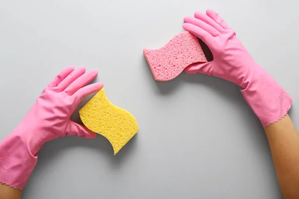 Mani femminili in guanti con spugne detergenti su sfondo grigio — Foto Stock