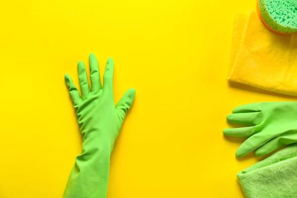 Hand in glove with cleaning supplies on color background — Stock Photo, Image