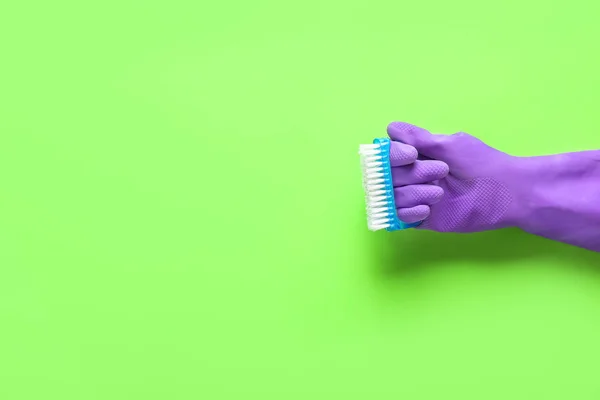 Female hand in glove holding cleaning brush on color background — Stock Photo, Image