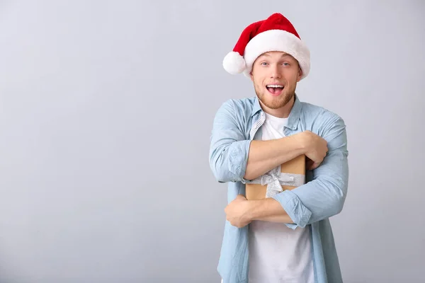 Young man with Christmas gift box on light background — Stock Photo, Image