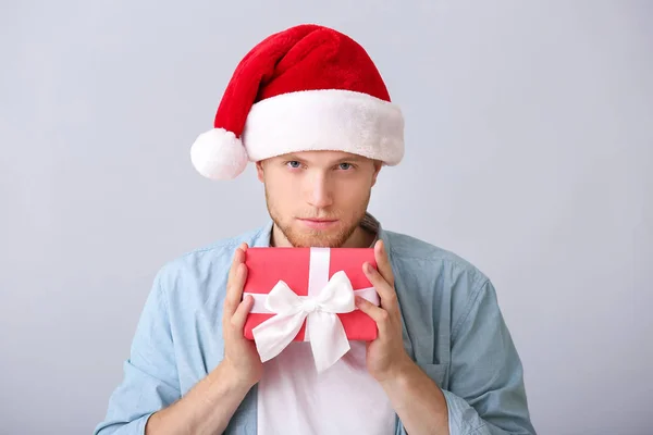 Young man with Christmas gift box on light background — Stock Photo, Image