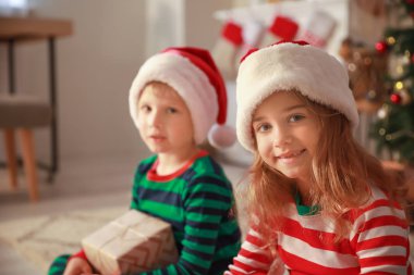 Evde Noel arifesinde Noel Baba şapkasevimli küçük çocuklar