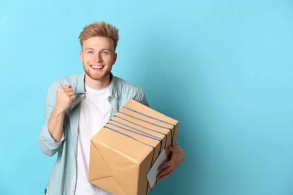 Happy young man with gift box on color background — Stock Photo, Image