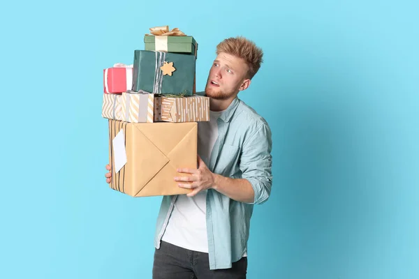 Renkli arka planda birçok hediye kutuları ile genç adam — Stok fotoğraf