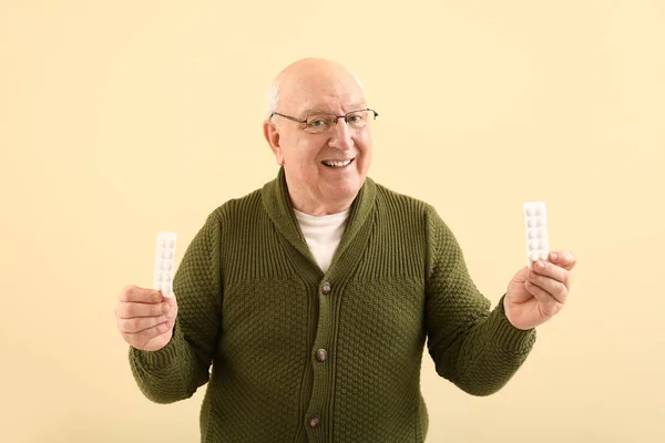 Elderly man with pills on color background — Stock Photo, Image