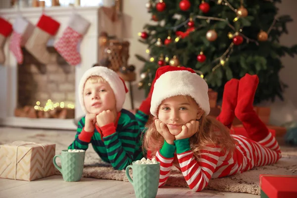 Söta små barn med koppar varm choklad på julafton hemma — Stockfoto