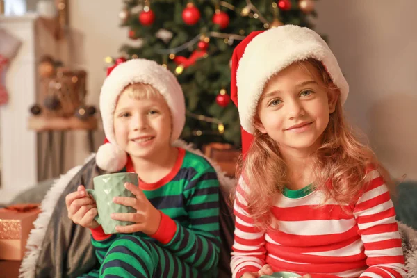 Söta små barn i Santa Claus hattar på julafton hemma — Stockfoto