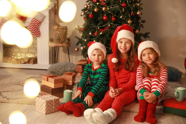 Söta små barn i Santa Claus hattar på julafton hemma — Stockfoto