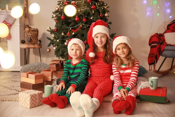 Cute little children in Santa Claus hats on Christmas eve at home — Stock Photo, Image