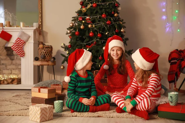 Söta små barn i Santa Claus hattar på julafton hemma — Stockfoto