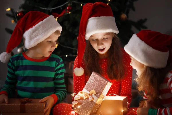 Cute little children opening magic Christmas gift at home — Stock Photo, Image