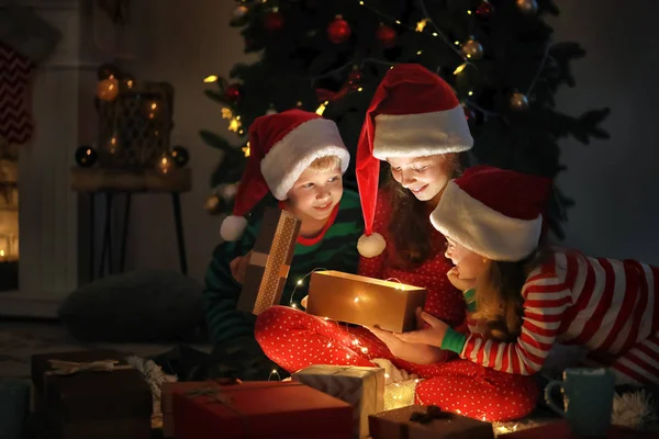 Cute little children opening magic Christmas gift at home — Stock Photo, Image