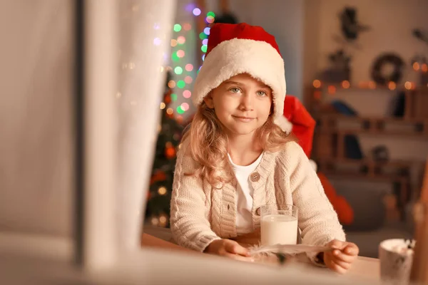 Carina la bambina che scrive lettera a Babbo Natale la vigilia di Natale a casa. Vista attraverso la finestra — Foto Stock