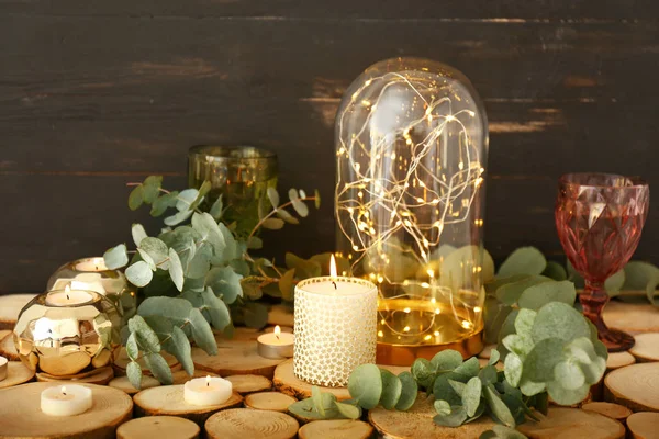 Beautiful burning candles with eucalyptus and glowing garland on table — Stock Photo, Image