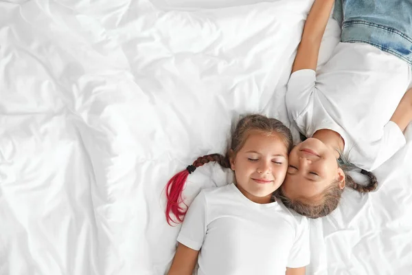 Portrait of cute twin girls lying on bed, top view — Stock Photo, Image