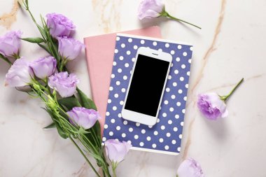 Cep telefonu, dizüstü bilgisayarlar ve çiçekler masada