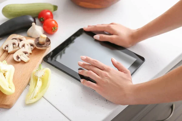 Woman with tablet computer cooking in kitchen — Stock Photo, Image