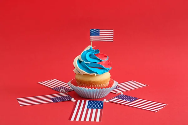 Tasty patriotic cupcake and USA flags on color background — Stock Photo, Image