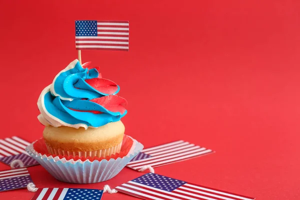 Tasty patriotic cupcake and USA flags on color background — Stock Photo, Image