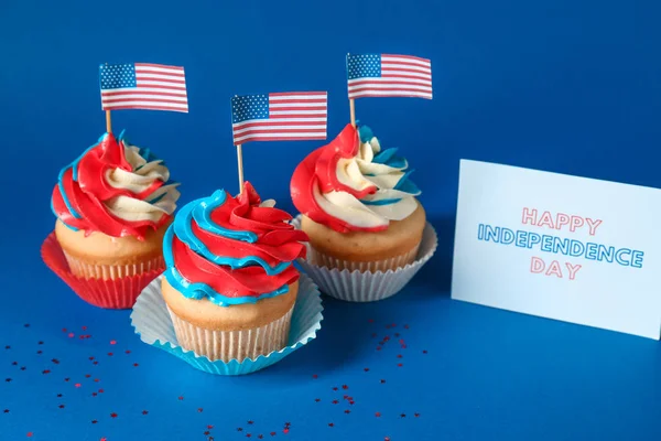 Smakelijke patriottische cupcakes en kaart voor Onafhankelijkheidsdag op kleur achtergrond — Stockfoto