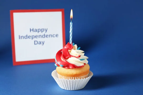 Saboroso cupcake patriótico e cartão com texto INDEPENDÊNCIA DE HAPPY DIA no fundo de cor — Fotografia de Stock