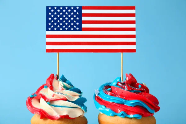 Tasty patriotic cupcakes and USA flag on color background — Stock Photo, Image