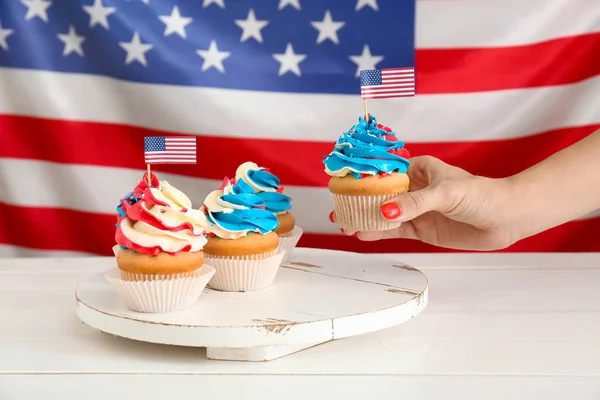 Woman taking tasty patriotic cupcake from table — Stock Photo, Image