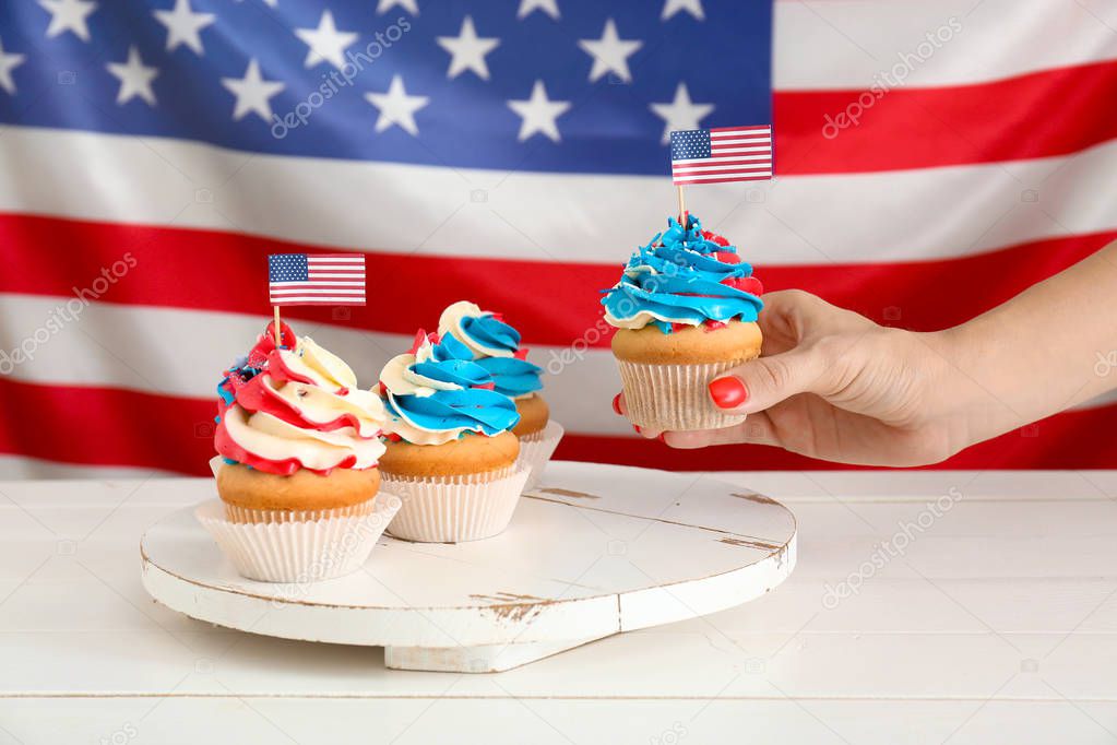 Woman taking tasty patriotic cupcake from table