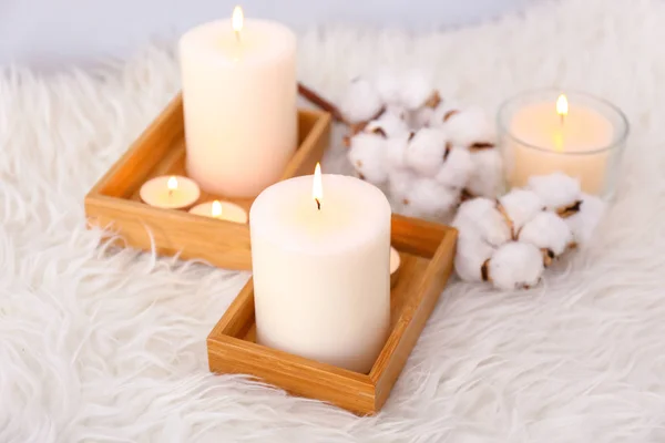 Composition with beautiful burning candles and cotton flowers on fluffy plaid — Stock Photo, Image