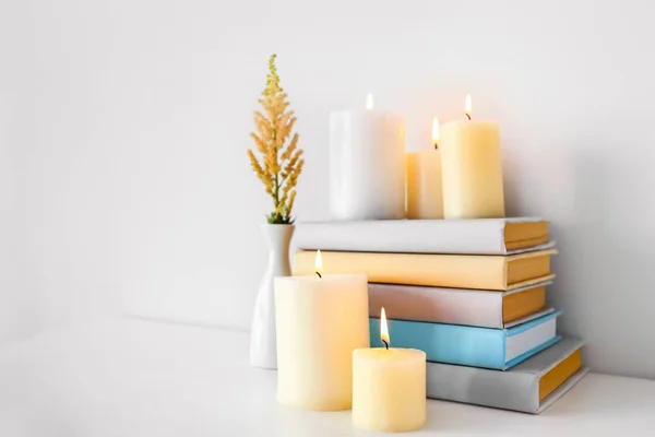 Composición con hermosas velas encendidas y libros sobre la mesa — Foto de Stock