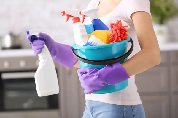 Kvinna med uppsättning av rengöringsmateriel i köket — Stockfoto