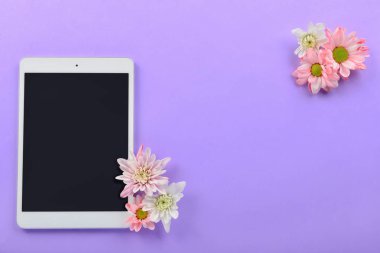 Modern tablet bilgisayar ve renkli arka planda çiçekler