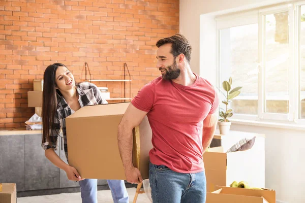 Young couple carrying boxes after moving into new house — Stock Photo, Image