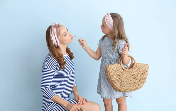 Μικρό κορίτσι εφαρμογή μακιγιάζ στο πρόσωπο της μητέρας της με φόντο το χρώμα — Φωτογραφία Αρχείου