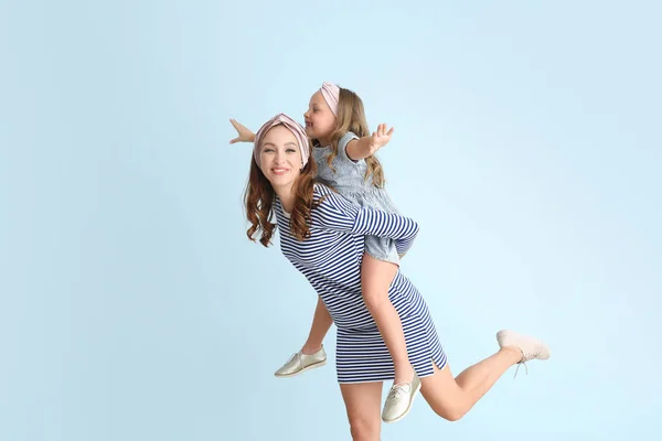 Beautiful woman and her little daughter having fun on color background — Stock Photo, Image